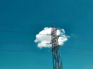 Utility lines in front of a blue sky with a cloud
