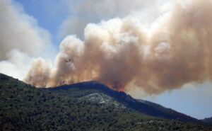 Wooded mountainside on file with plumes of smoke going into the air